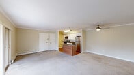 This 2-bedroom, 1-bathroom residence offers a thoughtfully designed single-level layout that maximizes functionality and comfort. The open-concept living and kitchen area serves as the heart of the home, where plush wall-to-wall carpeting flows through the spacious living room, accented by crown molding and a ceiling fan with pendant lighting. A sliding glass door floods the space with natural light and provides direct access to an outdoor area.

The kitchen is well-equipped with stainless steel appliances — including a refrigerator, gas range, microwave, and dishwasher — complemented by crisp white cabinetry, a subway tile backsplash, and a central island with a warm wood-toned base and dark countertop, ideal for casual dining or meal prep. Hardwood flooring anchors the kitchen area, creating a clean contrast to the carpeted living spaces.

Both bedrooms are generously proportioned, each featuring neutral carpeting, ample wall space, and windows that bring in natural light. The primary bedroom offers a comfortable footprint well-suited for a full furniture arrangement.

The bathroom features a full tub/shower combination adorned with elegant marble-style tile surround, adding a refined touch. A hallway with a dedicated closet rounds out this efficient and comfortable layout.