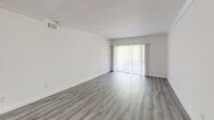 Located at 941 NE 169th St, Unit 218 in North Miami Beach, FL, this two-bedroom, one-bathroom residence offers a well-designed single-floor layout with thoughtfully updated finishes throughout. Light gray luxury vinyl plank flooring flows continuously through the living areas and bedrooms, creating a cohesive and contemporary feel.

The open kitchen is a standout feature, showcasing white shaker-style cabinetry extending to the ceiling, a mosaic tile backsplash, quartz countertops, and a full suite of stainless steel appliances including a side-by-side refrigerator with ice maker, dishwasher, and range. A peninsula with a quartz countertop provides added prep space and a natural division between the kitchen and living area.

The living room is bright and airy, featuring a large sliding glass door with vertical blinds that fills the space with natural light. Crown molding adds a refined touch to the main living areas and bedrooms. The spacious primary bedroom includes dual windows overlooking lush tropical greenery, offering serene natural views. The second bedroom also benefits from multiple windows with pleasant neighborhood views and includes a louvered closet. A dedicated hallway closet provides additional storage.

The bathroom is finished with large-format tile on both the floors and walls, complemented by a soaking tub and shower combination with a window for natural ventilation.