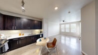 Located at Wolf Ranch Parkway in Georgetown, TX, this two-bedroom, two-bathroom residence offers a well-designed single-floor layout that maximizes functionality and comfort. The open-concept kitchen and living area form the heart of the home, where light wood-style flooring flows seamlessly throughout. The kitchen is appointed with rich, dark cabinetry, stainless steel appliances including a gas range and built-in microwave, a classic subway tile backsplash, light countertops, and a ceiling-mounted track lighting system. The adjacent living area is bright and airy, benefiting from a large window that invites natural light and a ceiling fan for added comfort. A glass-paneled exterior door provides additional light and access. Both bedrooms feature plush carpet, ceiling fans, and windows with views of surrounding greenery, creating a calm and restful atmosphere. The primary bedroom is a comfortable size and connects to a walk-in closet outfitted with multi-tier shelving and hanging rods. The two bathrooms are finished with tile flooring, dark vanity cabinetry, and light countertops. One bathroom features a glass-enclosed walk-in shower with tile surround, while the other offers a full vanity setup. The overall design is clean and contemporary, with neutral tones throughout creating a cohesive and inviting environment.
