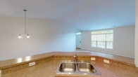 This single-floor unit offers a well-organized, open layout designed for comfortable everyday living. The kitchen is outfitted with warm honey-toned cabinetry, granite-style countertops, a double stainless steel sink, and white appliances including a refrigerator, electric range, microwave, and dishwasher. Hardwood-style flooring runs through the kitchen, transitioning to plush carpet in the adjoining living and dining areas. The dining space is accented by an elegant chandelier, while recessed lighting and a ceiling fan illuminate the open living zone. A window overlooking greenery brings in natural light, enhancing the bright, neutral palette throughout.

The primary bedroom connects directly to a private en suite bathroom featuring a single-sink vanity, a walk-in glass-enclosed shower, and tile flooring. A generously sized walk-in closet with wire shelving provides ample storage. A second full bathroom includes a tub-shower combination, vanity, and matching tile floors. The attached two-car garage offers substantial additional storage and vehicle space, complete with an automatic door opener. Overall, the unit presents a clean, functional, and move-in ready environment.
