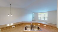 This single-floor unit offers a well-organized, open layout designed for comfortable everyday living. The kitchen is outfitted with warm honey-toned cabinetry, granite-style countertops, a double stainless steel sink, and white appliances including a refrigerator, electric range, microwave, and dishwasher. Hardwood-style flooring runs through the kitchen, transitioning to plush carpet in the adjoining living and dining areas. The dining space is accented by an elegant chandelier, while recessed lighting and a ceiling fan illuminate the open living zone. A window overlooking greenery brings in natural light, enhancing the bright, neutral palette throughout.

The primary bedroom connects directly to a private en suite bathroom featuring a single-sink vanity, a walk-in glass-enclosed shower, and tile flooring. A generously sized walk-in closet with wire shelving provides ample storage. A second full bathroom includes a tub-shower combination, vanity, and matching tile floors. The attached two-car garage offers substantial additional storage and vehicle space, complete with an automatic door opener. Overall, the unit presents a clean, functional, and move-in ready environment.