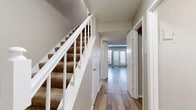 This two-story home offers a well-organized layout spread across two floors, providing comfortable living for its occupants. The main level features a living room with wood-look flooring and a French door entry that brings in natural light, creating an open and welcoming atmosphere. The kitchen is equipped with white cabinetry, white countertops, a double-basin sink, a dishwasher, and a mosaic tile backsplash, complemented by a window with blinds that fills the space with natural light. A hallway on this floor connects key living areas and houses a staircase with a white-railed banister and carpet-covered treads leading to the upper level. The main floor also includes a full bathroom featuring a tub-shower combination with warm earth-toned tile surround accented by a decorative border. Upstairs, two carpeted bedrooms offer a quiet retreat, each with neutral tones and textured ceilings. The primary bedroom is generously sized and includes a dedicated closet with built-in shelving and hanging rods. The second bedroom also features a closet with built-in organization and a window with natural light. A second full bathroom is located on the upper floor, complete with white vanity cabinetry. Both floors feature a hallway for convenient room access throughout the home.