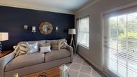 Located at 751 Mallet Hill Rd in Columbia, SC, this single-floor residence offers a thoughtfully designed layout with a seamless flow between living, dining, and private spaces. The living room is a standout area, highlighted by a bold navy accent wall, crown molding, and rich hardwood-style flooring. Natural light pours in through multiple windows, and a door leads to an exterior access point, enhancing the open, airy feel of the space. The kitchen is outfitted with white cabinetry, dark countertops, black appliances including a refrigerator and range, and hardwood-style flooring — combining practicality with clean, classic styling. The bedrooms are carpeted and each features a ceiling fan. One bedroom showcases a striking sage green accent wall with ample natural light, while another offers a walk-in closet with wire shelving. The bathrooms are well-appointed with white cabinetry, dark granite-style countertops, tile flooring, and tub-shower combinations accented with decorative tile details. Crown molding and consistent neutral wall tones throughout the home create a cohesive and polished aesthetic, making this residence a comfortable and stylish home in the heart of Columbia.