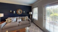 Located at 751 Mallet Hill Rd in Columbia, SC, this single-floor residence offers a thoughtfully designed layout with a seamless flow between living, dining, and private spaces. The living room is a standout area, highlighted by a bold navy accent wall, crown molding, and rich hardwood-style flooring. Natural light pours in through multiple windows, and a door leads to an exterior access point, enhancing the open, airy feel of the space. The kitchen is outfitted with white cabinetry, dark countertops, black appliances including a refrigerator and range, and hardwood-style flooring — combining practicality with clean, classic styling. The bedrooms are carpeted and each features a ceiling fan. One bedroom showcases a striking sage green accent wall with ample natural light, while another offers a walk-in closet with wire shelving. The bathrooms are well-appointed with white cabinetry, dark granite-style countertops, tile flooring, and tub-shower combinations accented with decorative tile details. Crown molding and consistent neutral wall tones throughout the home create a cohesive and polished aesthetic, making this residence a comfortable and stylish home in the heart of Columbia.