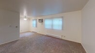 Located at 408 E Glendale Blvd in Valparaiso, Indiana, this single-floor unit offers a straightforward and functional layout well-suited for comfortable everyday living. The entry foyer provides a welcoming introduction to the space, opening into a generously sized carpeted living area. Large windows dressed with vertical blinds allow natural light to fill the room, while a ceiling fan and wall-mounted air conditioning unit ensure year-round climate comfort. Baseboard heating runs along the perimeter walls for additional warmth. The galley-style kitchen is efficiently designed with warm oak cabinetry lining both walls, offering ample storage and counter space. White appliances — including an electric range, refrigerator, microwave, and dishwasher — are included, and the tile flooring adds a clean, practical touch. The bedroom is a quiet, carpeted retreat featuring a large window with views of the outdoors and baseboard heating. The full bathroom is neatly appointed with tile flooring, a single-sink oak vanity with a large mirror, a full bathtub and shower combo, and a lighted vanity fixture overhead. Throughout the unit, neutral wall tones and consistent finishes create a cohesive and move-in ready environment.