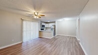 Located at 3024 N Powers Dr in Orlando, FL, this one-bedroom, one-bathroom unit offers a thoughtfully designed single-floor layout with a clean, modern aesthetic. Wood-look flooring flows consistently throughout the space, complemented by neutral wall tones and crisp white baseboards that create a bright, cohesive feel.

The open-concept living and kitchen area serves as the heart of the unit. The kitchen is well-equipped with stainless steel appliances — including a refrigerator, range, and microwave — paired with white cabinetry, light quartz countertops, and a peninsula with an undermount sink that doubles as a breakfast bar. A sputnik-style light fixture and access to a sliding glass door with vertical blinds add character and natural light to the living area, which also features a ceiling fan.

The bedroom is a comfortable, well-proportioned room with its own ceiling fan, direct access to the bathroom, and a dedicated walk-in closet outfitted with wire shelving on both sides. The full bathroom includes a tub/shower combo with white tile surround, a quartz-topped vanity with under-cabinet storage, and a framed mirror.

A separate laundry room provides additional utility space, housing the water heater and washer hookup connections. Textured ceilings appear throughout, adding a familiar residential character to this practical and move-in-ready unit.