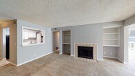 Located at 3100 Long Meadow Ct in Raleigh, NC, this single-floor home offers a well-designed layout with a neutral gray color palette and textured ceilings throughout. The living room serves as a central gathering space, highlighted by a tile-surround fireplace flanked by built-in shelving units, and a pass-through window connecting to the kitchen. A sliding glass door in an adjacent room fills the space with natural light and provides outdoor access. The kitchen features white cabinetry, a gas range, and wood-style flooring, with a conveniently tucked-in in-unit washer and dryer accessible through louvered bifold doors. The bedrooms are carpeted and generously sized, each offering closet storage; one bedroom includes a double closet with built-in rods and direct access to a bathroom, while another benefits from multiple windows and a ceiling fan. The bathrooms are clean and functional, featuring white vanity cabinetry, large mirrors, and tub-shower combinations. Wood-style flooring in the wet areas adds a warm contrast to the soft carpet found throughout the living spaces, creating a comfortable and cohesive home.