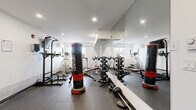 Located at 728 Meaford Ave in Langford, BC, this fitness room offers a compact yet efficiently utilized space designed to support a well-rounded workout routine. The room features durable rubber flooring throughout, crisp white walls, and recessed pot lighting that keeps the environment bright and functional.

The space is thoughtfully equipped with a varied selection of cardio machines, including a treadmill, stationary spin bikes, and an elliptical trainer, providing ample options for cardiovascular exercise. A large wall-mounted mirror spans one side of the room, enhancing the sense of space and allowing users to monitor their form during workouts.

For strength training, the room includes a multi-function cable machine, a weight bench with barbells, a pull-up and dip station, and freestanding Century heavy punching bags — catering to both resistance and combat-style training. Additional accessories such as step platforms and a motivational fitness poster round out the amenities.

A wall-mounted flat-screen TV adds a touch of convenience for entertainment during workouts. Natural light filters in through a window on one wall, contributing to a welcoming atmosphere. The room's practical layout maximizes every corner, making it a well-appointed fitness facility for residents at this Langford address.