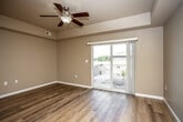 This single-floor residence offers a well-organized layout with a variety of thoughtfully designed spaces. The open living area makes an immediate impression with its rich wood-look hardwood flooring, a defined tray ceiling, and a ceiling fan with integrated lighting. Natural light flows generously through a sliding glass door that opens to a private balcony, providing outdoor views and a seamless indoor-outdoor connection.

The entryway, illuminated by a pendant light fixture, transitions smoothly into the spacious living area, where an open archway connects to the kitchen. The kitchen is equipped with rich cherry-toned cabinetry, granite-style countertops, stainless steel appliances including a refrigerator, electric range, and built-in microwave, along with a double-basin stainless steel sink.

The bedrooms feature plush wall-to-wall carpeting, neutral-toned walls, and generous closet space with built-in shelving. The bathrooms are finished with tile flooring, dark wood vanities, white countertops, and large mirrors. One bathroom includes a full tub-shower combination. A dedicated laundry area houses a full-sized washer and dryer with overhead wire shelving, adding practical convenience to the overall layout.