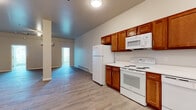 This single-floor unit offers a thoughtfully designed layout with a clean, modern aesthetic throughout. The kitchen is a standout feature, equipped with rich warm-toned wood cabinetry extending both above and below the countertops, white appliances including an electric range, built-in microwave, dishwasher, and refrigerator, all set against bright white countertops. Light hardwood-style flooring runs consistently throughout the unit, lending a cohesive and contemporary feel to every room.

The open living area is generously proportioned, featuring a ceiling fan, baseboard heating, and access to natural light through large windows. A structural column adds a distinctive architectural element to the main living space, while two windows at the far end of the room invite ample daylight.

The bedrooms are bright and comfortable, each featuring large windows with outdoor views, wall-mounted mini-split heating and cooling units, and baseboard heaters for efficient climate control year-round. The bathroom is finished with neutral tones, a white vanity with under-sink storage, a medicine cabinet mirror, and brushed nickel fixtures, creating a clean and functional space. The overall ambiance is fresh, neutral, and move-in ready.