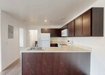 Located at 35410 Van Born Road in Wayne, Michigan, this 2-bedroom, 2-bathroom unit offers a practical and well-designed single-floor layout. The open-concept kitchen and living area serves as the heart of the unit, showcasing rich dark espresso cabinetry that reaches toward the ceiling, light countertops, a peninsula with an integrated sink, and white appliances including a refrigerator, range, and built-in microwave. The kitchen flows seamlessly into the living area, which features light wood-look plank flooring throughout and crisp white walls that create a clean, bright atmosphere. A large window and exterior door in the living space allow natural light to fill the room. Both bedrooms are comfortably sized, with the primary bedroom offering a closet and easy access to the kitchen area. The bathrooms feature dark wood vanities with light countertops, mirrors with overhead lighting, and full bathtub-shower combinations with wood-look flooring consistent with the rest of the unit. An in-unit laundry area adds everyday convenience. The overall design emphasizes a neutral, modern aesthetic with consistent finishes throughout, making for a cohesive and functional living space.