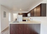 Located at 35410 Van Born Road in Wayne, Michigan, this 2-bedroom, 2-bathroom unit offers a practical and well-designed single-floor layout. The open-concept kitchen and living area serves as the heart of the unit, showcasing rich dark espresso cabinetry that reaches toward the ceiling, light countertops, a peninsula with an integrated sink, and white appliances including a refrigerator, range, and built-in microwave. The kitchen flows seamlessly into the living area, which features light wood-look plank flooring throughout and crisp white walls that create a clean, bright atmosphere. A large window and exterior door in the living space allow natural light to fill the room. Both bedrooms are comfortably sized, with the primary bedroom offering a closet and easy access to the kitchen area. The bathrooms feature dark wood vanities with light countertops, mirrors with overhead lighting, and full bathtub-shower combinations with wood-look flooring consistent with the rest of the unit. An in-unit laundry area adds everyday convenience. The overall design emphasizes a neutral, modern aesthetic with consistent finishes throughout, making for a cohesive and functional living space.