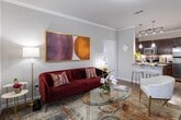 Located at 30000 FM-2978 in Magnolia, Texas, this single-floor residence offers a thoughtfully designed layout with a cohesive blend of modern finishes and warm, inviting interiors throughout. The kitchen is a standout feature, showcasing rich dark cabinetry, granite countertops, a tile backsplash, and a full suite of stainless steel appliances including a refrigerator, microwave, and range. A peninsula with an undermount sink and pendant lighting above creates an ideal space for casual dining or meal prep, while hardwood-style flooring ties the room together. The living area is bright and welcoming, with crown molding, neutral walls, and generous natural light filtering through window treatments, complemented by warm wood flooring. Both bedrooms are comfortably sized, each featuring crown molding, hardwood-style floors, natural light from windows dressed with elegant teal drapes and wooden blinds, and ample room for furnishings. The bathroom is finished with granite countertops, dark cabinetry, large-format tile surrounding a soaking tub and shower combination, and hardwood-style flooring, offering a clean and functional retreat. Throughout the space, crown molding and consistent flooring lend a polished, unified aesthetic.