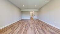 This newly constructed three-floor home offers a well-designed layout across five bedrooms, three bathrooms, and multiple living areas. The main floor is the largest level, featuring an open-concept kitchen equipped with slate-blue shaker cabinetry, a stainless steel farmhouse sink, subway tile backsplash, pendant lighting, and stainless steel appliances, including a dishwasher. The kitchen flows seamlessly into the living and dining areas, where warm hardwood floors extend throughout. Sliding glass doors lead to a freshly built wooden deck, offering pleasant outdoor views. The bathrooms are finished with a clean, modern aesthetic, featuring grey vanities, black hardware accents, and a mix of wood-look and tile flooring. The upper floor houses the bedrooms, each carpeted for comfort and equipped with ceiling fans. Bedrooms include built-in closets, and the primary bedroom provides a generous, well-proportioned retreat. The lower floor offers additional living space with hardwood-style flooring, a wall-mounted mini-split unit, and sliding doors that bring in natural light. Two staircases connect the floors, enhancing circulation throughout the home. The neutral grey palette and clean white trim present a fresh, move-in ready atmosphere.