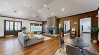 Located at 2400 Spring Rain Dr in Spring, TX, this generously sized single-story community clubhouse offers a thoughtfully designed layout across a broad, open floor plan. Rich hardwood flooring flows throughout, complemented by dark wood trim that lends a warm, sophisticated character to every room.

The centerpiece of the main gathering area is a dramatic floor-to-ceiling stacked stone fireplace, anchoring the expansive lounge space beneath soaring vaulted ceilings. Multiple seating arrangements invite relaxation, while large windows framed with bamboo shades bathe the interiors in natural light and offer views of the outdoor pool area.

The modern kitchen is a standout feature, boasting a striking waterfall-edge quartz island, sleek white cabinetry, stainless steel appliances, and a textured wood accent wall — a refined space suited for community events and gatherings.

A dedicated fitness center is equipped with cardio machines, weight equipment, and floor-to-ceiling mirrors, all beneath ceiling fans for added comfort. Private office spaces connected by glass-paned doors provide functional work areas with a polished aesthetic.

Additional highlights include a cozy secondary lounge with pool views, a hallway connecting all areas seamlessly, and a dedicated Amazon Hub package locker station for resident convenience.