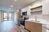 This well-designed one-bedroom, one-bathroom unit at 4651 Dodge St in Omaha, Nebraska offers a thoughtfully arranged open-concept floor plan that maximizes every square foot. Wood-look plank flooring runs throughout the space, providing a warm, cohesive aesthetic from room to room.

The kitchen is a standout feature, showcasing a sleek two-tone design with warm wood-grain lower cabinetry paired with crisp white upper cabinets and open shelving. A subway tile backsplash adds texture, while a clean white countertop and undermount sink complete the look. Stainless steel appliances — including a refrigerator, electric range, over-the-range microwave, and dishwasher — provide a full suite of modern conveniences. The kitchen opens directly into the combined dining and living area, creating an inviting, airy atmosphere enhanced by a large window that draws in natural light.

The bedroom offers a comfortable, private retreat and is accompanied by a dedicated closet equipped with shelving and a hanging rod for organized storage. The bathroom features warm wood-tone cabinetry with a clean white countertop, a full tub-shower combination, and consistent wood-look flooring that ties the space together. Neutral gray walls throughout lend a clean, contemporary feel to the entire unit.