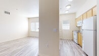This single-floor unit offers a clean, light-filled interior defined by consistent light wood-style vinyl flooring that runs throughout the space. The open-concept kitchen is equipped with warm honey-toned cabinetry, a granite-style countertop breakfast bar, and white appliances including a refrigerator, electric range, built-in microwave, and dishwasher. Flush-mount ceiling lights illuminate the kitchen, while a ceiling fan serves the adjacent living area, adding both comfort and airflow. A structural column subtly separates the kitchen from the living space without disrupting the open feel.

Natural light enters generously through multiple windows fitted with horizontal blinds, and a glass-paneled exterior door in the living area provides outdoor access and additional brightness. The living space features neutral cream-toned walls that complement the flooring and create a calm, cohesive aesthetic throughout.

A hallway lined with classic six-panel white doors leads to the private rooms, each offering a spacious, neutral canvas ready for personalization. The bedrooms feature the same light flooring and cream walls, maintaining a uniform and airy feel. A bathroom with vanity and standard fixtures completes the layout. Overall, the unit presents a well-maintained, functional living environment with a bright and welcoming atmosphere.