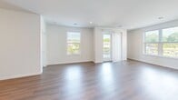 Located on Payne Street in Dover, NH, this thoughtfully designed single-floor home offers four bedrooms and two full bathrooms across a well-appointed layout. The open-concept kitchen and living area serves as the heart of the home, featuring warm wood-tone cabinetry, white upper cabinets, a subway tile backsplash, a central island with pendant lighting, and a full suite of stainless steel appliances. The living room is bathed in natural light from multiple windows and a glass balcony door that opens to an outdoor balcony with neighborhood views, all set on durable hardwood-style flooring. The bedrooms are carpeted for comfort, with natural light provided by well-placed windows. The primary bedroom includes access to a dedicated walk-in closet with built-in shelving and recessed lighting. Both bathrooms are finished in a clean, modern style—one featuring a glass-enclosed walk-in shower and a wood-vanity with a white quartz countertop, and the other offering a full soaking tub and shower combination with white subway tile surround. Throughout the home, a neutral white and natural wood palette creates a bright, cohesive aesthetic that is both modern and inviting.