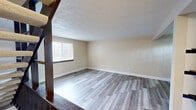 Located at 5550 Old William Penn Hwy in Murrysville, PA, this 2-bedroom, 2-bathroom home is spread across three floors, offering a practical and well-appointed layout. The entry level houses a garage, an entrance area, and a laundry room, providing convenient ground-floor utility space. Carpeted staircases with dark wood railings connect all three levels, adding a classic touch to the vertical circulation throughout the home. The main living level features an open-plan dining room and kitchen combination alongside a living room. The kitchen stands out with rich dark wood cabinetry, light granite countertops, stainless steel appliances including a refrigerator, dishwasher, and range, and durable wood-look flooring. The upper floor is dedicated to the two bedrooms and two bathrooms. The spacious primary bedroom offers generous room with natural light from a window and a closet with dark wood bifold doors. The second bedroom also features wood-look flooring, a textured ceiling, a closet, and a window with outdoor views. The two bathrooms are distinctly styled — one features a vessel sink, granite vanity, and decorative cabinetry, while the other offers a full tub-shower combo, a dark granite vanity, and tile accent details. Throughout, neutral tones and wood-look flooring create a cohesive, move-in-ready aesthetic.