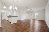 This single-floor residence offers a thoughtfully designed layout that maximizes comfort and functionality. Rich hardwood-style flooring flows throughout the main living areas, complemented by crisp white walls and elegant crown molding that add a polished, refined character to the space.

The open living room is bright and airy, featuring a ceiling fan with light fixture and a window that invites natural light, while crown molding frames the room with classic detail. Adjacent to the living room, the dining area is highlighted by a stylish chandelier and continues the warm hardwood-style flooring.

The galley-style kitchen is well-equipped with stainless steel appliances including a refrigerator and range, white cabinetry, dark granite-style countertops, and a double-basin stainless steel sink — offering both practicality and a clean aesthetic.

The bedroom is generously sized, carpeted for comfort, and features a ceiling fan, multiple windows for natural light, and direct access to a large walk-in closet outfitted with wire shelving systems on multiple walls, providing ample storage.

The bathroom includes hardwood-style flooring, a tiled shower, a white vanity with dark countertop, and a large mirror. A dedicated laundry area and additional closet space round out this well-organized and move-in-ready home.