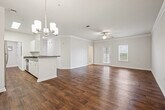 This single-floor residence offers a thoughtfully designed layout that maximizes comfort and functionality. Rich hardwood-style flooring flows throughout the main living areas, complemented by crisp white walls and elegant crown molding that add a polished, refined character to the space.

The open living room is bright and airy, featuring a ceiling fan with light fixture and a window that invites natural light, while crown molding frames the room with classic detail. Adjacent to the living room, the dining area is highlighted by a stylish chandelier and continues the warm hardwood-style flooring.

The galley-style kitchen is well-equipped with stainless steel appliances including a refrigerator and range, white cabinetry, dark granite-style countertops, and a double-basin stainless steel sink — offering both practicality and a clean aesthetic.

The bedroom is generously sized, carpeted for comfort, and features a ceiling fan, multiple windows for natural light, and direct access to a large walk-in closet outfitted with wire shelving systems on multiple walls, providing ample storage.

The bathroom includes hardwood-style flooring, a tiled shower, a white vanity with dark countertop, and a large mirror. A dedicated laundry area and additional closet space round out this well-organized and move-in-ready home.