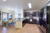 Located at 4560 S Balsam Way in Denver, Colorado, this well-appointed two-bedroom, two-bathroom residence offers comfortable single-floor living with a thoughtfully designed open-concept layout. The kitchen is a standout feature, showcasing rich dark espresso cabinetry, a full suite of black appliances including a refrigerator, range, and built-in microwave, generous counter space, and a central island with a sink — all finished with wood-look flooring that flows seamlessly throughout the main living areas. The kitchen opens directly into the dining area, which is brightened by a sliding glass door offering outdoor access and natural light, and connects to a welcoming living room featuring large windows dressed with layered curtains, filling the space with an airy, relaxed ambiance. The primary bedroom is a comfortable retreat with a ceiling fan, natural light from a large window, and plush carpeting. The bathrooms are finished with dark wood vanities, stone-toned countertops, and a tub-shower combination. Two closets provide ample storage throughout the unit. A dedicated in-unit laundry area adds everyday convenience. The overall design combines neutral tones, modern fixtures, and functional spaces to create a cohesive and inviting home.