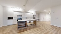 Located at 4331 34th St S in Saint Petersburg, FL, this thoughtfully designed single-story home offers five bedrooms, two bathrooms, and a generous, flowing layout. The open-concept kitchen is a standout feature, showcasing floor-to-ceiling white cabinetry, a subway tile backsplash, stainless steel appliances including a built-in microwave, electric range, dishwasher, and French door refrigerator, plus a large island with warm wood shelving and pendant lighting. Vaulted ceilings amplify the sense of space in the main living area, which is bathed in natural light and finished with light-toned luxury vinyl plank flooring. Ceiling fans are present throughout for added comfort. The bedrooms are well-proportioned; some feature plush carpeting, while others continue the LVP flooring, and each is served by one of seven closets offering excellent storage. The primary bedroom includes access to a private balcony, bringing in outdoor views. The bathrooms are finished in a clean, contemporary style with large-format white tile flooring, modern floating vanities, and a tub-shower combination. A dedicated laundry area and a hallway connecting the rooms complete this practical and stylish home.