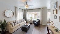 This single-floor residence offers a cohesive and comfortable living experience defined by a neutral gray-and-white color palette, wood-look flooring in the main areas, and plush carpet in the bedrooms. The living room is a welcoming space filled with natural light streaming through multiple large windows adorned with blinds and sheer curtains. A ceiling fan overhead and built-in shelving add both function and character to the room. The kitchen is efficiently designed with gray cabinetry, granite-style countertops, and black appliances including a range, over-the-range microwave, and refrigerator. Adjacent to the kitchen, the dining area features a glass-top round table set beside a large window that offers views of the surrounding exterior. The primary bedroom is generously sized with sliding glass doors opening to a private outdoor space, a ceiling fan, and direct access to an en-suite bathroom. A second bedroom also includes a ceiling fan, plush carpet, a closet, and convenient access to a full bathroom. Both bathrooms are fitted with tub-shower combinations. Throughout the space, textured ceilings, soft lighting, and thoughtful décor details contribute to a warm, lived-in ambiance that feels both practical and inviting.
