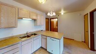 Located at 3501 Tenth Ave S in Moorhead, Minnesota, this single-floor unit offers a well-organized layout designed for comfortable everyday living. The kitchen is a functional centerpiece, outfitted with light oak cabinetry providing generous storage, laminate countertops, and a full suite of white appliances including a refrigerator, electric range, built-in microwave, and dishwasher. A double-basin sink and a peninsula with additional cabinet space add practicality, while a chandelier overhead lends a touch of warmth to the area. Tile-style flooring runs throughout the kitchen and extends into adjacent spaces. The bedrooms are carpeted and feature ceiling fans with light fixtures, baseboard heating, and windows with blinds that bring in natural light and neighborhood views. One bedroom includes a walk-in closet with built-in shelving, offering excellent storage capacity. The unit includes two bathrooms: one with a full tub-shower combination, a large vanity mirror, and a single-sink vanity, and a second with a spacious vanity, tile flooring, and ample room to move. Textured ceilings are consistent throughout, and warm wood-toned trim and doors add cohesion to the overall design. The layout flows intuitively between living, kitchen, and bedroom areas, making efficient use of the available space.