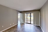 Located at 25 Featherwood Ct in Silver Spring, Maryland, this well-appointed one-bedroom, one-bathroom residence offers a thoughtfully organized single-floor layout. The living room is a standout feature, showcasing durable wood-style plank flooring in a warm gray tone and floor-to-ceiling vertical blinds that frame a large sliding glass door leading to a private balcony. Natural light pours into this open area, creating a bright and welcoming atmosphere with views of the surrounding greenery.

Adjacent to the living area, the dining space flows seamlessly into the galley-style kitchen, which is equipped with warm wood cabinetry, dark granite-style countertops, black appliances including a gas range and refrigerator, and a skylight that keeps the space well-lit.

The generously sized bedroom features the same wood-style flooring, a large window for natural light, a double-door closet, and access to an additional walk-in closet outfitted with dual hanging rods and shelving for abundant storage. The full bathroom includes a tiled shower-tub combination. A hallway connects the main living areas, with multiple closets throughout providing practical storage solutions. The neutral gray palette throughout lends the space a clean, modern aesthetic.