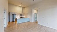 Located in Silverdale, WA, this well-appointed 3-bedroom, 2-bathroom residence offers a thoughtfully designed single-level layout with modern finishes throughout. The open-concept living area features light wood-tone flooring, soaring ceilings, and large windows that invite abundant natural light. Sliding glass doors lead to a private balcony, extending the living space outdoors with views of the surrounding neighborhood and tree line.

The kitchen is a standout feature, showcasing light grey cabinetry with matte black hardware, white quartz countertops, a subway tile backsplash, stainless steel appliances including a gas range and built-in microwave, and a peninsula with dramatic pendant lighting overhead. A matte black faucet adds a refined touch to the undermount sink.

The generously sized primary bedroom is carpeted for comfort and features a ceiling fan and a large window framing serene wooded views. The two additional bedrooms are similarly finished with plush carpet and ample natural light. Four closets provide excellent storage throughout.

Both bathrooms are finished in a clean, contemporary style with white cabinetry, quartz countertops, matte black fixtures, and light wood-tone tile flooring. The primary bath includes a glass-enclosed walk-in shower. A hallway connects all rooms with ease, completing this polished and functional home.