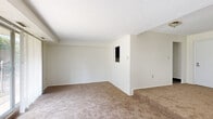 Located at 2200–2220 High St. in Cuyahoga Falls, Ohio, this single-floor unit offers three bedrooms, two bathrooms, a kitchen, a hallway, and a closet within a well-organized layout. The living area features warm neutral carpeting, textured ceilings, and large sliding glass door access with vertical blinds that allow generous natural light and views of the surrounding greenery. The galley-style kitchen is well-appointed with dark espresso cabinetry, granite-look countertops, wood-style vinyl plank flooring, and standard appliances including a refrigerator, range, and dishwasher. The spacious primary bedroom is generously proportioned, offering plush carpeting, a wide sliding-door closet with built-in hanging rod, and a bright window. The additional bedrooms share similarly neutral, carpeted finishes and natural light. The bathrooms feature dark wood vanities with white countertops, large mirrors with overhead lighting, and wood-style tile flooring. A connecting hallway links the bedrooms and bathrooms, providing a practical and efficient flow throughout. The unit's clean, neutral palette and functional design make it a versatile and comfortable living space.