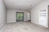 Located at 1309 Gatewood Dr in Auburn, Alabama, this single-story home offers a well-organized layout designed for comfortable living. The main living area is finished with soft carpeting and neutral gray walls, creating a clean, versatile backdrop. It connects seamlessly to a dedicated dining space, with the kitchen accessible through a defined opening. The kitchen is equipped with stainless steel appliances including a refrigerator, range, over-the-range microwave, and dishwasher, complemented by white cabinetry, granite-style countertops, and a subway tile backsplash — providing both style and functionality. A second living or sitting area features vaulted ceilings, a sliding glass door that brings in natural light and outdoor views, and a built-in shelving unit with cabinet storage below. The bedrooms are carpeted and offer ample space, with at least one featuring a bifold closet. Additional bedrooms are bright and well-proportioned with natural light from windows. The bathrooms include tub/shower combinations, white vanities with granite-style countertops, and wood-look flooring, offering a clean and updated aesthetic throughout.