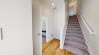 This well-designed three-story townhome in Longmont, Colorado offers a thoughtful layout spread across three levels, combining modern aesthetics with practical functionality. The entry level provides an attached garage and a flexible office space, ideal for working from home. The main living floor showcases a bright, open-concept design where the living room, dining area, and kitchen flow seamlessly together. The living room features sage green accent walls, warm hardwood-style flooring, and large sliding glass doors that fill the space with natural light. The contemporary kitchen is appointed with slate-blue cabinetry, granite countertops, a central island, stainless steel appliances, and a subway tile backsplash. A sleek half bathroom with a floating vanity and wood-look flooring completes this level. Upstairs, the two bedrooms are carpeted and bathed in natural light from large windows offering pleasant outdoor views. The primary bedroom connects directly to an en-suite bathroom featuring granite countertops and modern fixtures. A second full bathroom with granite countertops and a shower serves the additional bedroom. Throughout the home, clean white walls, recessed lighting, and ceiling fans contribute to a fresh, contemporary ambiance.