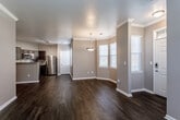 Located at 14644 Broadmoor St in Overland Park, Kansas, this well-appointed single-floor home offers a cohesive, modern aesthetic throughout its thoughtfully designed layout. The living and dining areas showcase rich, dark hardwood-style flooring that extends through the main living spaces, complemented by neutral gray walls, crisp white crown molding, and white baseboards. A charming bay window area in the dining space is highlighted by a pendant light fixture, allowing natural light to filter in through slatted blinds. The kitchen is a functional highlight, featuring dark espresso cabinetry, light granite-style countertops, a mosaic tile backsplash, and a full suite of stainless steel appliances including a refrigerator, range, microwave, and dishwasher. Track lighting overhead adds a modern touch. The bedrooms offer plush carpeting, ceiling fans, and ample natural light through double windows. The primary bedroom is generously proportioned with access to both a private bathroom and a walk-in closet. Bathrooms are finished with dark vanity cabinetry, granite-style countertops, hardwood-style flooring, and tub-shower combinations with clean white tile surrounds. The overall ambiance is clean, contemporary, and move-in ready.