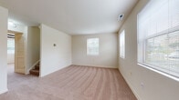 This two-floor residence offers a practical and comfortable layout spread across multiple well-defined rooms. The entry level welcomes visitors through a paneled front door with decorative transom windows, opening into a carpeted living area bathed in natural light from a nearby window. A staircase connects the two floors, maintaining a seamless flow throughout the home.

The kitchen is equipped with warm oak cabinetry, a stainless steel sink, laminate countertops, and white appliances including a refrigerator and dishwasher. A stacked washer and dryer unit is conveniently integrated within the kitchen area, adding functional value. The adjacent half-bath features light tile flooring for easy maintenance.

The bedrooms are carpeted and filled with natural light courtesy of multiple windows dressed with blinds. One standout bedroom features exposed dark wood ceiling beams and a ceiling fan, lending a distinct architectural character to the space. Additional bedrooms offer views of surrounding greenery, creating a calm and refreshing atmosphere.

The full bathroom includes white wall tile, a vanity with wood cabinetry, and a mirror. Throughout the home, neutral wall tones and soft carpeting create a cohesive, understated palette well-suited for a variety of furnishing styles.