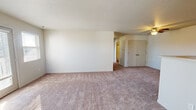 This single-floor residence at Woods Edge Apartment Homes in Muncie, Indiana offers a practical and comfortable layout designed for everyday living. The spacious living area is finished with plush wall-to-wall carpeting and neutral-toned walls, creating a clean, versatile canvas. A ceiling fan adds both comfort and functionality, while a sliding glass door and adjacent window allow natural light to pour in and provide access to the outdoors. The kitchen is well-appointed with white cabinetry, light countertops, and a full suite of black appliances including a refrigerator and range. Wood-look vinyl flooring runs throughout the kitchen, which also features an in-unit washer and dryer area tucked conveniently at the back. A pass-through counter connects the kitchen to the main living space, enhancing the open feel. Multiple bedrooms are carpeted and each feature windows with blinds that bring in soft, natural light, offering comfortable and private retreats. The bathroom includes a full tub and shower combination with chrome fixtures, wood-look flooring, and a vanity with ample counter space. Throughout the home, a consistent neutral palette and clean finishes contribute to a bright, welcoming atmosphere.
