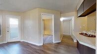 This single-floor unit offers a well-organized layout with a variety of distinct living spaces. The main living area is a generous, open room featuring durable wood-style flooring and a striking brick fireplace with a dark shiplap surround, flanked by windows that allow ample natural light. A door adjacent to the fireplace provides direct exterior access.

The kitchen is designed in a U-shaped configuration, outfitted with rich, dark espresso cabinetry, light stone-look countertops, and black appliances including a refrigerator, range, microwave, and dishwasher. A window with vertical blinds adds natural light to the workspace.

Bedrooms are carpeted for comfort and each features windows that brighten the space; at least one bedroom includes a ceiling fan. The hallway connects the main living area to the private rooms and bathrooms, maintaining an efficient flow throughout the unit.

The bathroom showcases a wide vanity with dark cabinetry matching the kitchen, light countertops, and wood-style flooring. Throughout the unit, textured ceilings, neutral warm-toned walls, and white trim provide a cohesive, clean aesthetic.