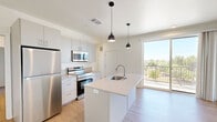 Located at 630 N Kelly Ave in Oklahoma City, OK, this thoughtfully designed one-bedroom, two-bathroom unit offers a clean, modern aesthetic on a single floor. Light wood-style flooring runs throughout the entire space, creating a cohesive and airy feel.

The open-concept living and kitchen area serves as the heart of the unit. The kitchen features sleek white cabinetry, a center island with a built-in sink and light countertops, stainless steel appliances including a refrigerator, range, and microwave, and stylish pendant lighting overhead. A ceiling fan keeps the living area comfortable, and a bold green entry door adds a distinctive pop of color.

The generously sized primary bedroom is bathed in natural light from two large windows with outdoor views of surrounding greenery, and is equipped with a ceiling fan for added comfort. The room provides direct access to a dedicated laundry area, which houses a stacked washer and dryer unit alongside built-in shelving for storage convenience.

The two bathrooms are finished in a clean, minimal style with light wood flooring, white vanities with modern hardware, and tiled shower areas. A dedicated closet provides additional organized storage. The overall ambiance of the unit is bright, clean, and move-in ready, with a consistent neutral palette throughout.