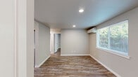 Located at 1126 Sleater Kinney Rd SE in Lacey, Washington, this single-story unit offers a practical and modern layout with two bedrooms and one full bathroom. Consistent wood-look plank flooring flows throughout the entire space, lending a warm, cohesive feel to every room. Neutral gray tones on the walls complement the light-colored trim and recessed ceiling lighting found across the unit.

The kitchen is a standout feature, outfitted with white shaker-style cabinetry, light countertops, a stainless steel dishwasher, an electric range, and a built-in microwave. A window above the sink allows natural light to brighten the workspace.

Both bedrooms are well-proportioned with clean, neutral walls and windows that invite natural light. The primary bedroom features a window overlooking greenery, while the second bedroom includes a window with neighborhood views and an electrical panel on the wall. Each room is served by wall-mounted heating units, ensuring comfort year-round.

The bathroom is finished with a full-size tub and shower combo, featuring brushed nickel hardware and clean white surroundings. The unit's compact but efficient floor plan makes excellent use of its space, offering a functional and move-in ready home in a convenient Lacey location.