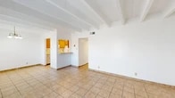 Located at 120 Cornell Dr SE in Albuquerque, New Mexico, this single-floor 2-bedroom, 2-bathroom home offers a functional and well-organized layout. The open living and dining area is a central highlight, featuring distinctive exposed beam ceilings, light tile flooring, and bright white walls that create a clean, airy atmosphere. A chandelier adds a touch of warmth to the dining space, which is bathed in natural light from a large window fitted with vertical blinds.

The kitchen is laid out in a galley style, equipped with light wood cabinetry, ample counter space, a built-in dishwasher, electric range, and a pass-through window that connects it visually to the dining area. A hallway leads to the two bedrooms, each featuring the same exposed beam ceilings and tile flooring, with windows that bring in natural light and views of the surrounding neighborhood. Four closets provide generous storage throughout the home.

The primary bathroom includes a double-sink vanity with a large mirror, offering added convenience. The second bathroom provides additional functionality for residents and guests. With four closets distributed throughout, storage is plentiful. The consistent tile flooring, neutral color palette, and Southwestern-inspired beam ceilings give this Albuquerque home a cohesive and practical character.
