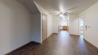 This single-floor residence offers a well-organized layout with a thoughtful blend of comfort and functionality. The living room serves as the centerpiece of the home, featuring rich, dark hardwood-style flooring, a classic white-framed fireplace with a wood mantel, a ceiling fan with integrated lighting, and a textured ceiling. A sliding vertical blind panel provides access to natural light and outdoor views, creating a bright and welcoming atmosphere. A wide hallway with the same hardwood-style flooring connects the living area to the kitchen, which is fully equipped with warm honey-toned wood cabinetry, white appliances including a range, dishwasher, and refrigerator, a double-basin sink beneath a window, and ample counter and storage space arranged in a U-shaped configuration. The residence includes two bedrooms, each finished with neutral wall-to-wall carpeting, vertical blind-covered windows that let in natural light, and clean, understated walls that offer flexibility for personalization. Two bathrooms provide practical convenience; one features a sliding glass-enclosed shower stall with a single vanity and hardwood-style flooring, while the other is appointed with a vanity, toilet, and a natural light-admitting window. Throughout the home, consistent finishes and neutral tones create a cohesive, move-in-ready environment.