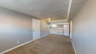 Located at 1024 Forest Ct in Kansas City, KS, this single-floor unit offers a straightforward, functional layout designed for comfortable everyday living. The main living area is open and spacious, finished with wall-to-wall carpet in a neutral tan tone and painted in soft gray throughout, creating a clean, cohesive aesthetic. Flush-mount ceiling lighting illuminates the space, and a standard entry door provides direct access.

The kitchen is efficiently arranged along one wall and transitions seamlessly from the living area. It features white cabinetry — both upper and lower — paired with a light countertop, a double-basin stainless steel sink, a white electric coil-top range, and a full-size white refrigerator. Tile flooring in the kitchen provides a practical contrast to the carpeted living spaces.

The bedroom is a well-proportioned room with carpet, gray walls, a textured ceiling, ceiling light fixture, and a built-in closet with bifold doors. A window allows for natural light. An additional room with carpet and a window provides flexible use as a second bedroom or office.

The bathroom includes a full-size soaking tub and shower, finished with neutral beige tile surround that extends the full height of the walls, offering a polished, durable finish.