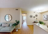 Located at 4495 Emerald Vista in Lake Worth, Florida, this single-floor residence offers a well-organized layout designed for comfortable everyday living. The living room serves as a welcoming centerpiece, featuring warm beige walls, wood-style flooring, and a sliding glass door that opens to a private outdoor patio, allowing natural light to fill the space. Adjacent to the living area, the dedicated dining space is defined by a chandelier overhead and offers a cozy setting for meals.

The galley-style kitchen is efficiently designed with white cabinetry, light countertops, a double sink, and white appliances, with additional utility space conveniently located just beyond.

The unit includes two bedrooms, each carpeted and bathed in natural light from large windows with outdoor views of the surrounding greenery. Both rooms offer a calm, restful atmosphere with ample wall space and closet access. The full bathroom features wood-style flooring, a white vanity with cabinet storage, a large mirror with overhead lighting, and a shower-tub combination.

Throughout the home, textured ceilings, neutral warm tones, and consistent flooring materials create a cohesive and inviting aesthetic. A central hallway connects all rooms, contributing to a functional and efficient flow across the entire residence.