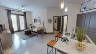 Located at 2807 Wildwood St in Corinth, TX, this single-story residence presents a clean, modern aesthetic characterized by polished concrete floors, crisp white walls, and charcoal-toned door frames and doors throughout. The open-concept living and kitchen area forms the heart of the unit, where pendant lighting hangs above a granite-topped kitchen island with bar seating. The kitchen is equipped with medium-toned wood cabinetry, granite countertops, stainless steel appliances including a microwave and refrigerator, a black electric range, and a tiled backsplash. Ample closet and pantry storage is accessible directly from the kitchen area.

The living room benefits from natural light through large windows dressed with floor-length curtains, creating a welcoming atmosphere. Two well-proportioned bedrooms each feature polished concrete floors, generous closet space, and large windows. One bedroom includes a walk-in closet.

Both bathrooms are finished with wood-toned vanities, granite countertops, framed mirrors with lighted fixtures, and tiled surrounds. One bathroom features a soaking tub and shower combination, while the second offers a walk-in shower. The overall design maintains a consistent contemporary palette throughout.