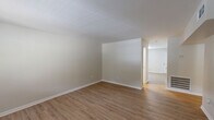Located at 2553 Lower Wetumpka Rd in Montgomery, Alabama, this single-story 2-bedroom, 1-bathroom home offers a clean, move-in-ready layout with consistent light wood-look flooring running throughout every room. The living room serves as a welcoming entry point, featuring a paneled front door and a window that draws in natural light, creating a bright and open atmosphere. The combined kitchen and living area is well-appointed with white shaker-style cabinetry, laminate countertops, an under-cabinet range hood, and a window that provides additional ventilation and natural illumination. The layout flows efficiently through a central hallway connecting all main areas. The spacious primary bedroom is among the most notable features of the home, offering generous square footage, a ceiling fan with light, and a window with outdoor views, along with a closet accessed through a paneled interior door. The second bedroom is comparably sized, also equipped with a ceiling fan, window, and HVAC vent. The bathroom features a full tub-shower combination with white tile surround and brushed nickel fixtures. Neutral beige walls, clean white trim, and consistent flooring throughout lend the home a cohesive, understated aesthetic well-suited for comfortable everyday living.