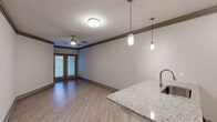 Located at 13220 Foster St in Overland Park, KS, this single-floor, one-bedroom, one-bathroom residence offers a thoughtfully designed layout with modern finishes throughout. The open-concept kitchen and living area serves as the heart of the home, featuring light wood-tone flooring, crown molding, and a ceiling fan that enhances airflow and comfort. The kitchen is outfitted with white cabinetry, stainless steel appliances — including a refrigerator, range, and microwave — and a granite-topped peninsula with an undermount sink, illuminated by stylish pendant lighting overhead. The living area extends toward glass French doors that invite natural light and provide outdoor access. The spacious bedroom is finished with plush carpet, a ceiling fan, and a large window with outdoor views. It connects to a generously sized walk-in closet equipped with wire shelving and hanging rods, offering ample storage. A second closet provides additional organization options. The full bathroom features a tub/shower combination, granite vanity countertop, and clean white finishes. A dedicated laundry area adds everyday convenience. Neutral tones and consistent detailing throughout create a cohesive, move-in-ready living environment.