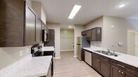 Located at 710 Congaree Rd in Greenville, SC, this single-floor residence offers a thoughtfully designed layout across a comfortable footprint. The open-concept kitchen is a standout feature, showcasing rich dark-brown cabinetry, marble-look countertops, a kitchen island with a sink, stainless steel appliances including a refrigerator, electric range with microwave, and dishwasher. Skylights and recessed lighting illuminate the kitchen and living areas, which are finished with warm light hardwood-style flooring that enhances the bright, neutral color palette throughout. The living area flows seamlessly from the kitchen, with a ceiling fan overhead and a glass-paneled front door that invites natural light. The bedroom is a generously sized retreat carpeted in plush neutral tones, fitted with a ceiling fan and two windows offering views of surrounding greenery. Dual doorways lead to a full bathroom and a dedicated walk-in closet outfitted with multi-tier wire shelving for ample storage. The bathroom features a full tub-shower combination, a dark-cabinet vanity with marble-look countertop, and light hardwood-style flooring, maintaining the cohesive modern aesthetic found throughout the space.