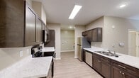 Located at 710 Congaree Rd in Greenville, SC, this single-floor residence offers a thoughtfully designed layout across a comfortable footprint. The open-concept kitchen is a standout feature, showcasing rich dark-brown cabinetry, marble-look countertops, a kitchen island with a sink, stainless steel appliances including a refrigerator, electric range with microwave, and dishwasher. Skylights and recessed lighting illuminate the kitchen and living areas, which are finished with warm light hardwood-style flooring that enhances the bright, neutral color palette throughout. The living area flows seamlessly from the kitchen, with a ceiling fan overhead and a glass-paneled front door that invites natural light. The bedroom is a generously sized retreat carpeted in plush neutral tones, fitted with a ceiling fan and two windows offering views of surrounding greenery. Dual doorways lead to a full bathroom and a dedicated walk-in closet outfitted with multi-tier wire shelving for ample storage. The bathroom features a full tub-shower combination, a dark-cabinet vanity with marble-look countertop, and light hardwood-style flooring, maintaining the cohesive modern aesthetic found throughout the space.