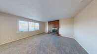 Located at 3115 Heritage Ct in Manhattan, Kansas, this two-bedroom, one-bathroom single-story home offers a well-organized layout across a comfortable footprint. The living area is a standout space, featuring plush carpeting, a textured ceiling, large windows that invite natural light, and a classic full brick fireplace with a gold-trimmed insert as a striking focal point. Adjacent to the living area, a built-in wood bookshelf adds both character and practical storage, with a clear sightline to the kitchen beyond. The kitchen is equipped with dark wood cabinetry, a white tile backsplash, white appliances including a full-size refrigerator and range, and granite-style countertops with a stainless steel double sink. A separate dining area features hardwood-style flooring, vertical blinds, and an overhead light fixture. Both bedrooms are carpeted; the primary bedroom includes a ceiling fan and a closet, while the secondary bedroom offers natural light through a window with blinds. The hallways connect the spaces cleanly, finished with hardwood-style flooring. The bathroom provides a full tub-shower combination with white subway tile surround and chrome fixtures, maintaining a clean, functional aesthetic throughout.